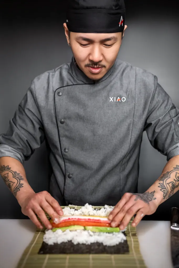 Ein Sushi Meister rollt eine frische Maki Rolle
