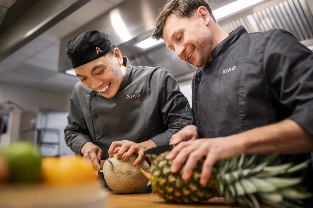 Zwei XIAO Mitarbeiter schneiden frisches Obst in der Gastro Küche