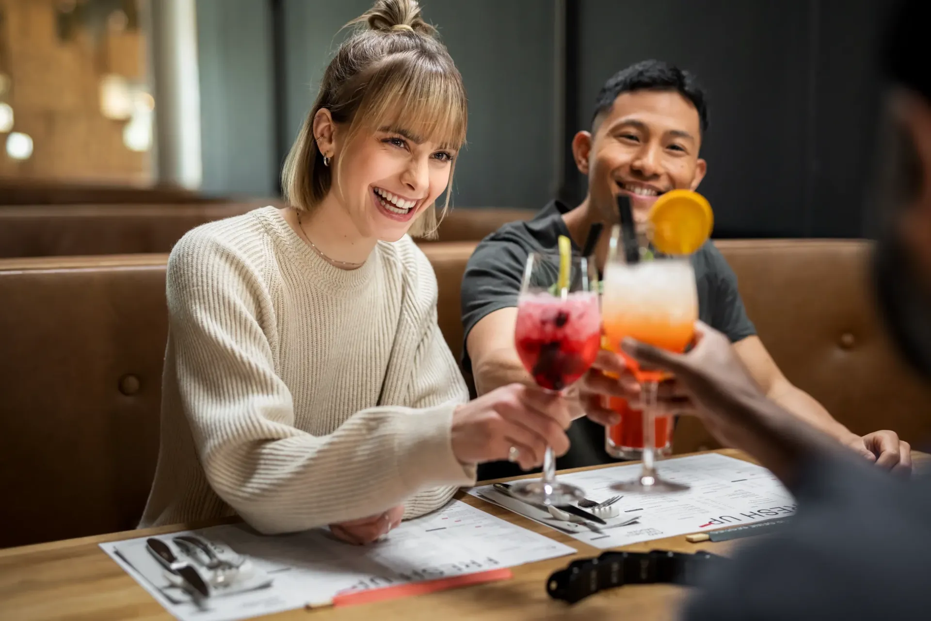 Freunde haben etwas zu feiern und stoßen in gemütlicher Atmosphäre mit Cocktails und Longdrinks an