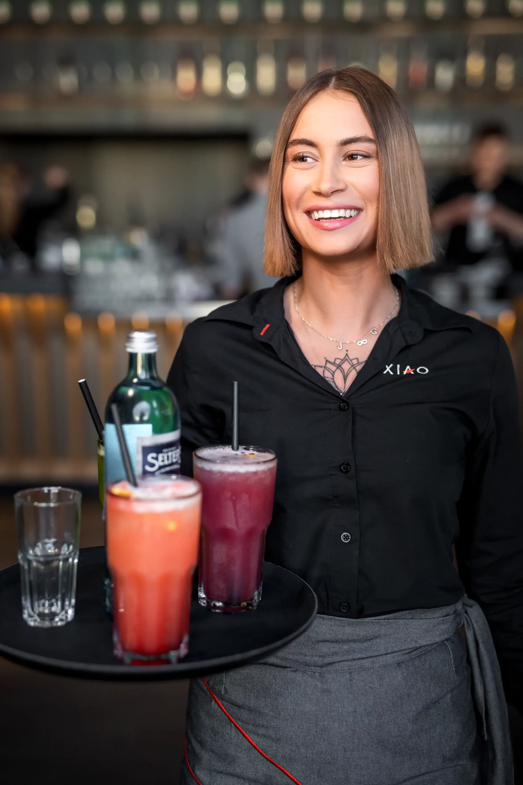 Eine Servicekraft im stilvoll eingerichteten Restaurant trägt ein Tablett mit Cocktails