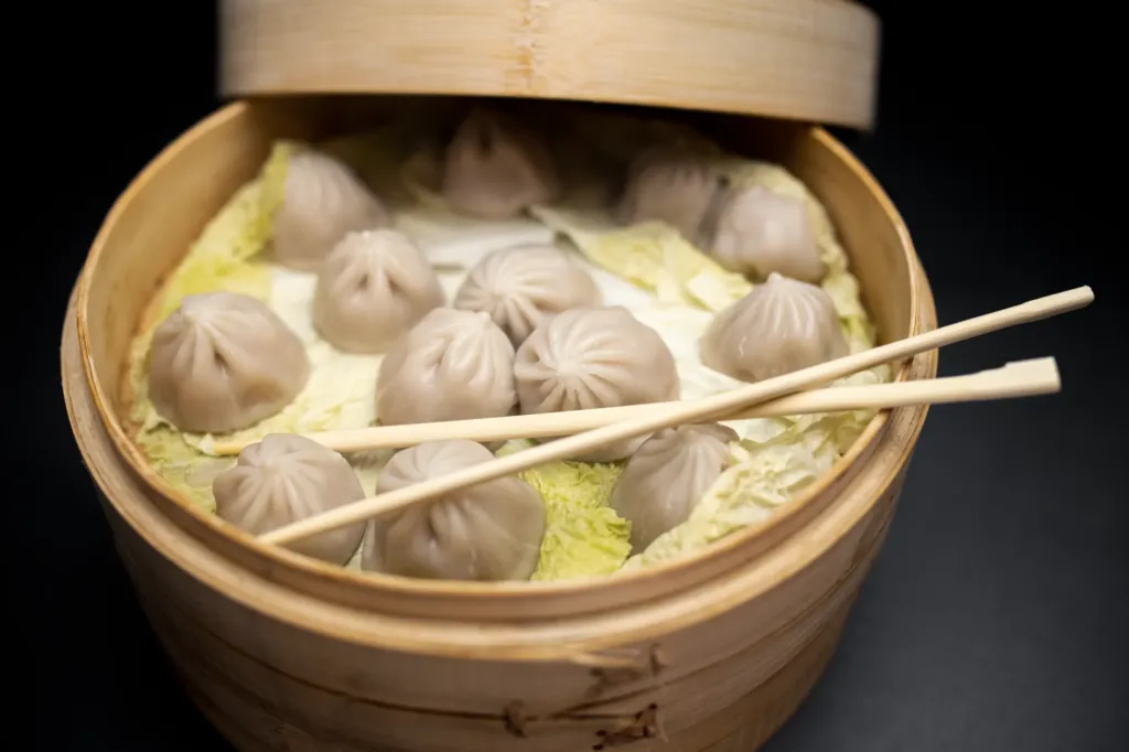 Teigtaschen in traditionell asiatischem Dampfgarkorb mit Stäbchen
