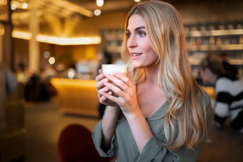 Eine Frau hält bei stimmungsvollem Licht ein Kaffeegetränk in den Händen
