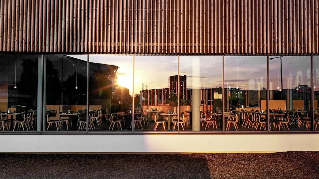 Von außen durch große Fenster fotografierter Sitzbereich im Restaurant