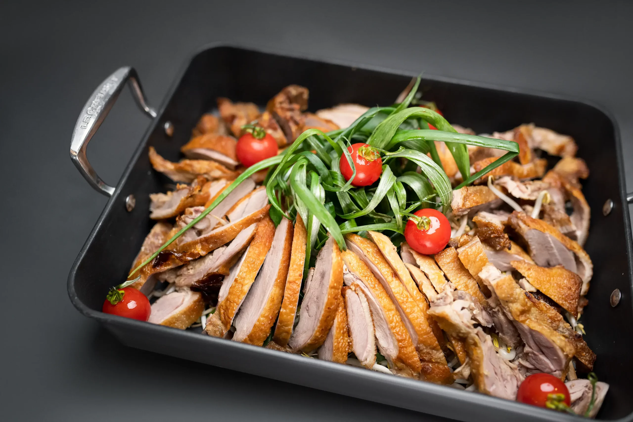 Eine eckige Pfanne mit knusprigen Streifen gebratener Ente.