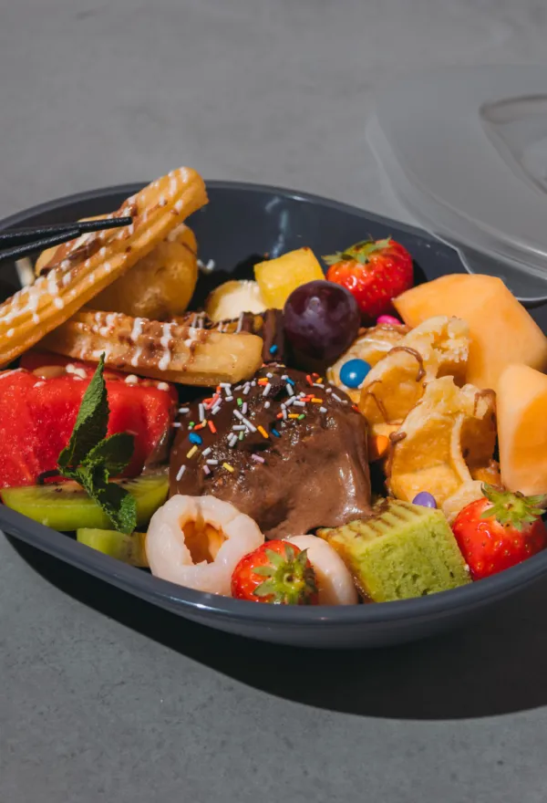 Take-away-Schale mit frischem Obst, Spießen und gebratenem Fleisch