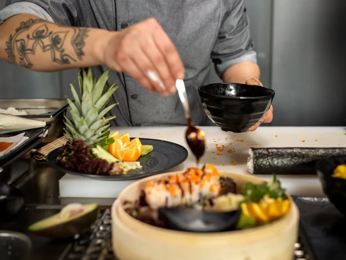 Koch bereitet Essen vor Ein Koch träufelt konzentriert Sauce auf frisches Obst und Gemüse